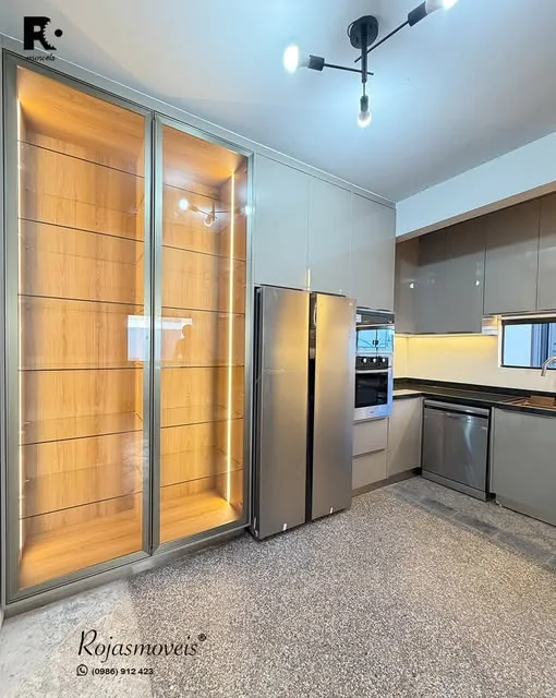 Cocina con pared de listones de madera, vitrina iluminada y torre de horno empotrada
